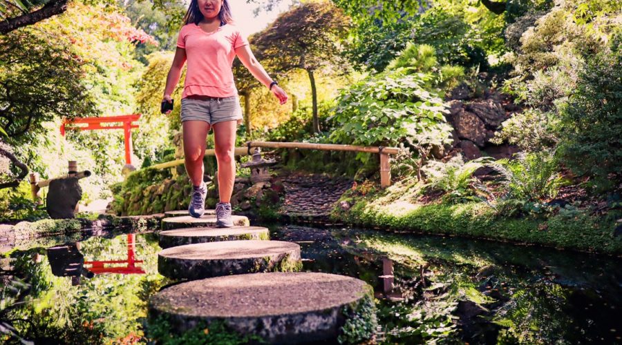 Mulher andando nas pedras do jardim japonês de Forest Glade Gardens em Mount Macedon